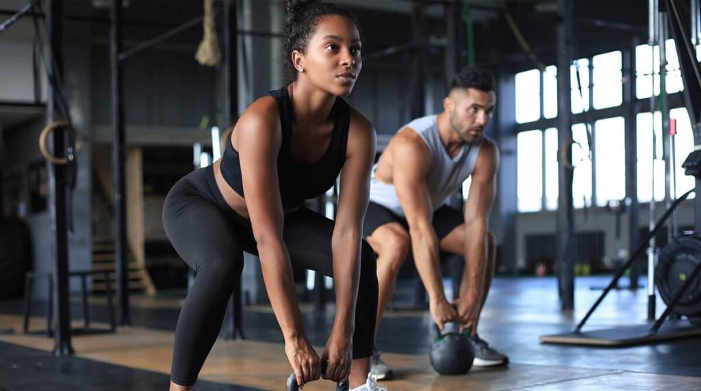 man and woman lifting kettlebells in the gym