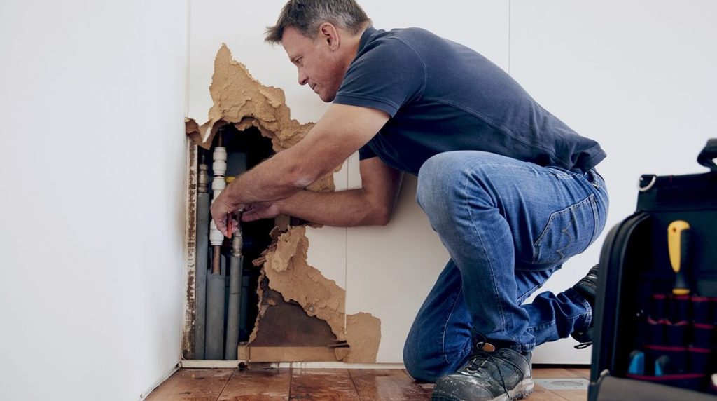 tradesperson fixing leaky pipe in rental property