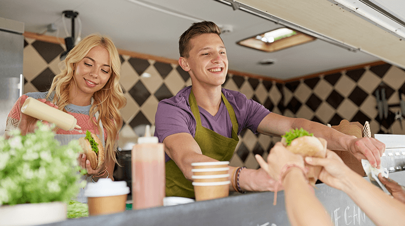 Two business owners serving food from a food truck