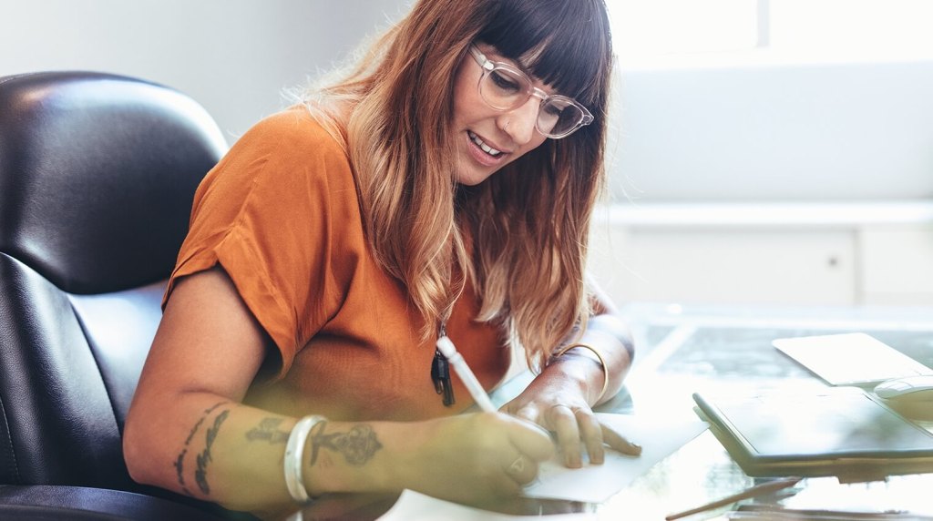 Marketing consultant making notes at her desk in her office