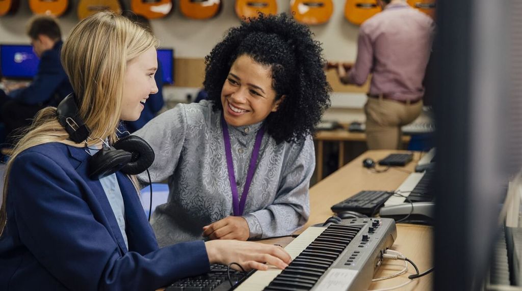 Music teacher giving lesson to student playing the keyboard