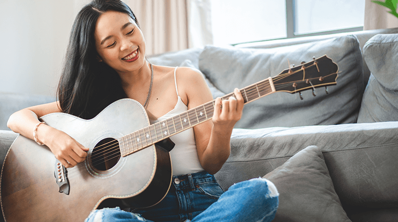 A woman playing a guitar at home