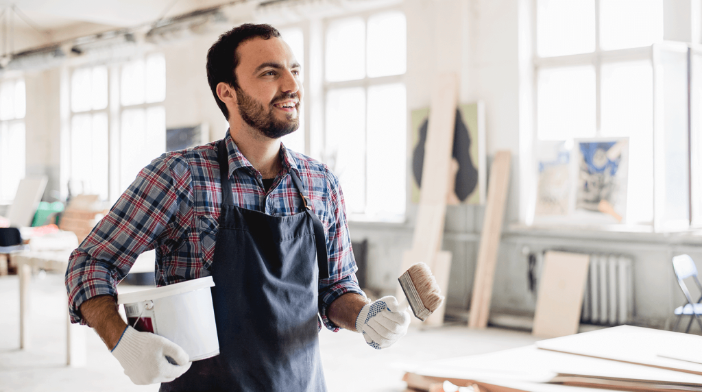 Painter and decorator holding a tub of wallpaper paste and a brush