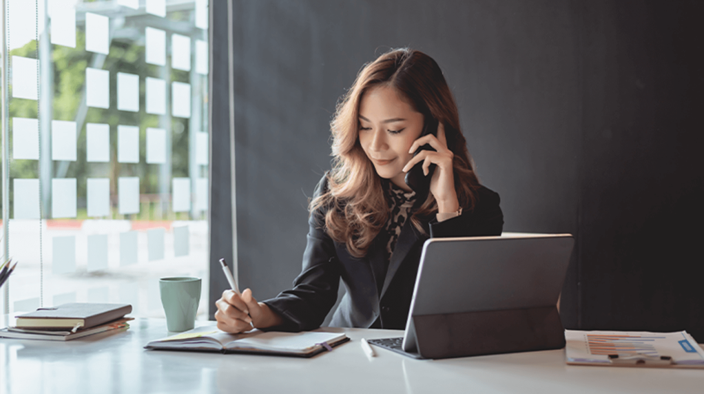 A smartly dressed woman on the phone and taking notes