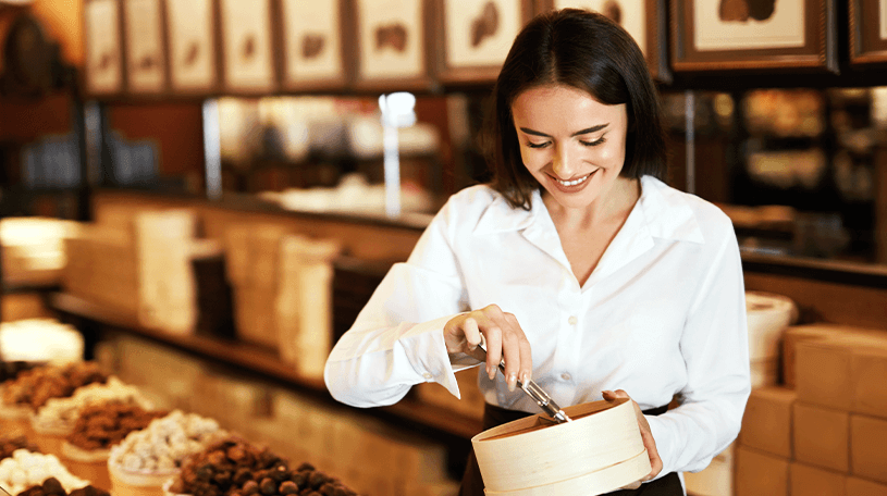 Female sweet shop worker scooping sweets into a paper bag