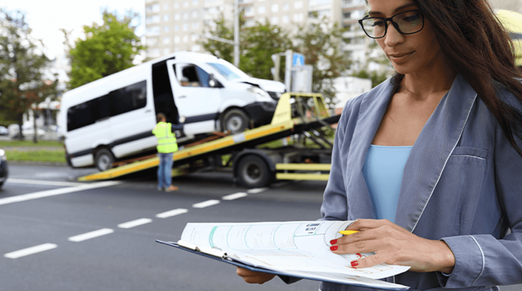 A business owner checking paper work while van is loaded on a truck