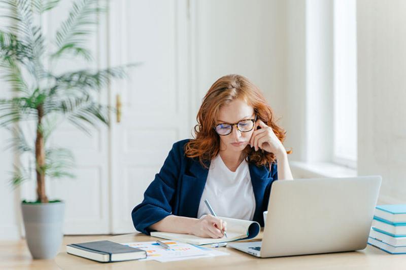 Woman writing notes with laptop
