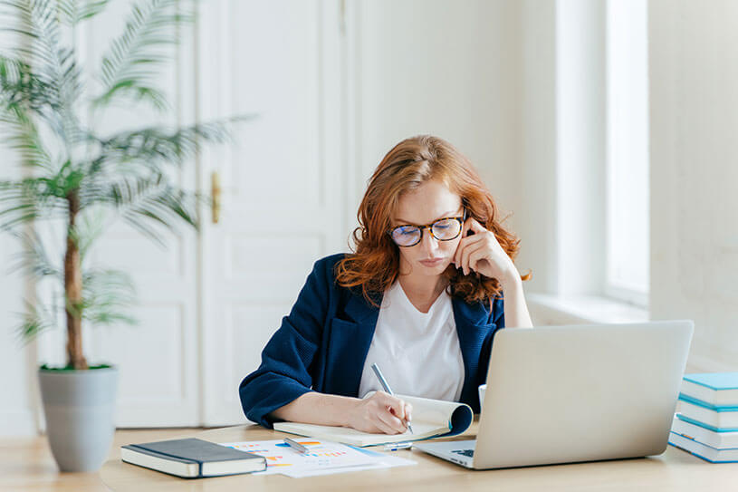 Woman writing notes with laptop