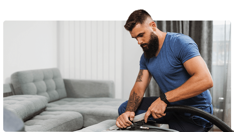 Carpet and upholstery clear - a man is cleaning a sofa with a professional ceaner