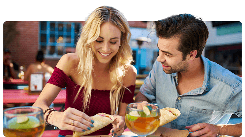 Food business: a woman and a man eating tacos and drinking cocktails