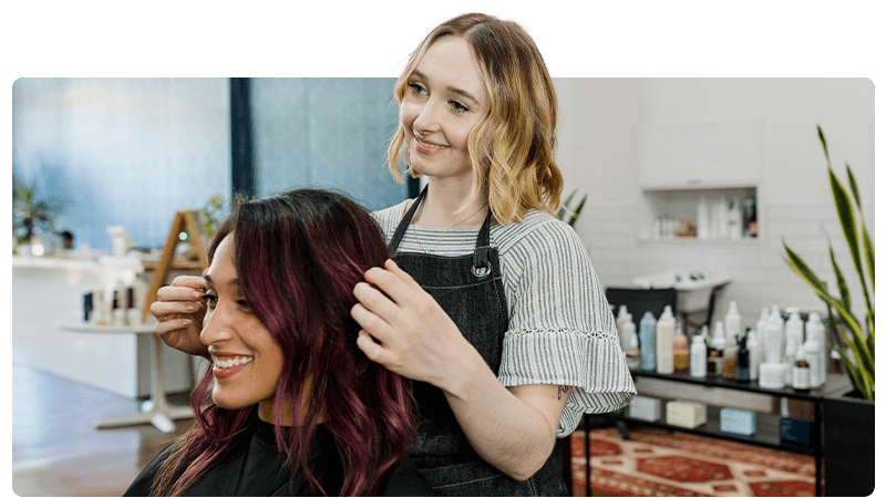 Two women in a hair salon with one styling the others hair