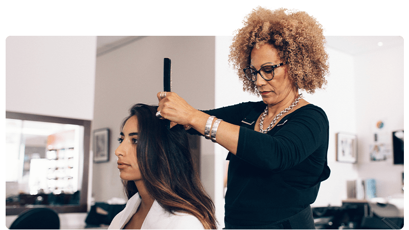 A hairdresser is styling a woman's hair in a hairdressers salon.