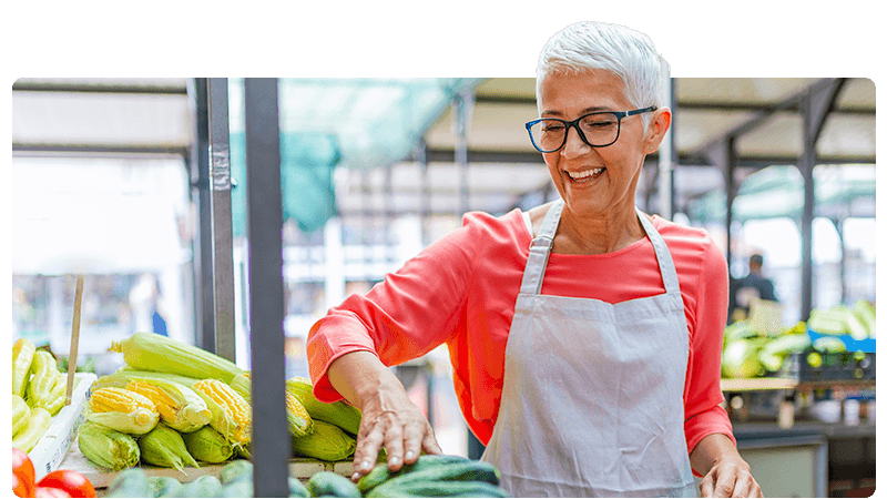 Woman market trader wearing an apron and organising vegetables