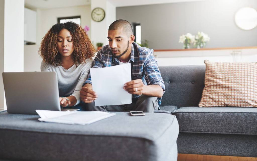 Young couple sitting on sofa reviewing their deposit protection scheme