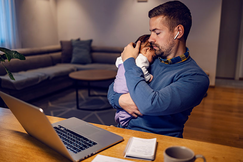 Self-employed dad holding baby during a break while working from home