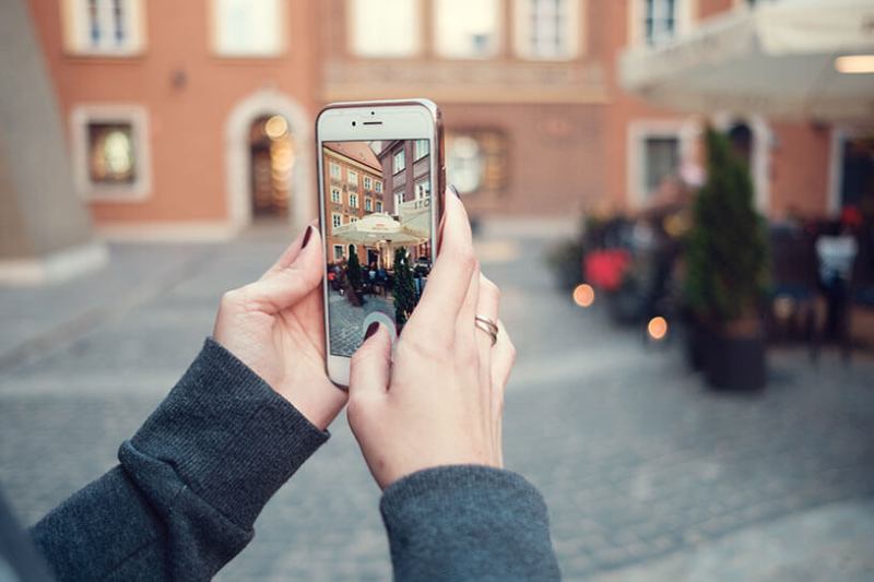 Woman's hands holding a phone to take an Instagram picture of a building