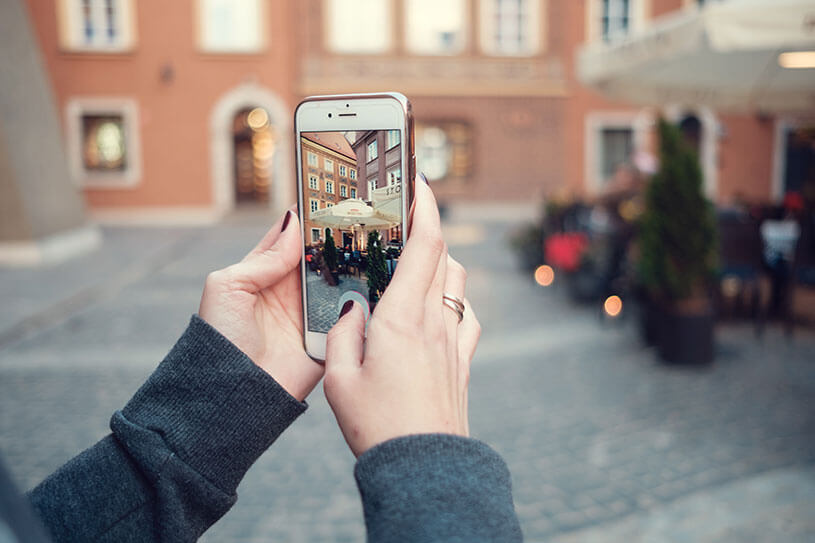 Woman's hands holding a phone to take an Instagram picture of a building