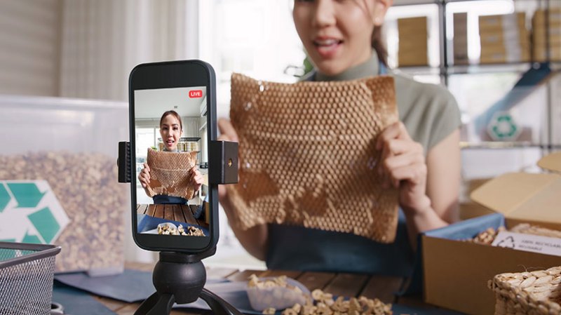 A woman using TikTok to advertise her business by holding products up to a phone camera