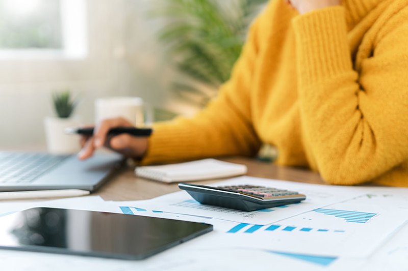Person in a yellow jumper works out their tax on a calculator