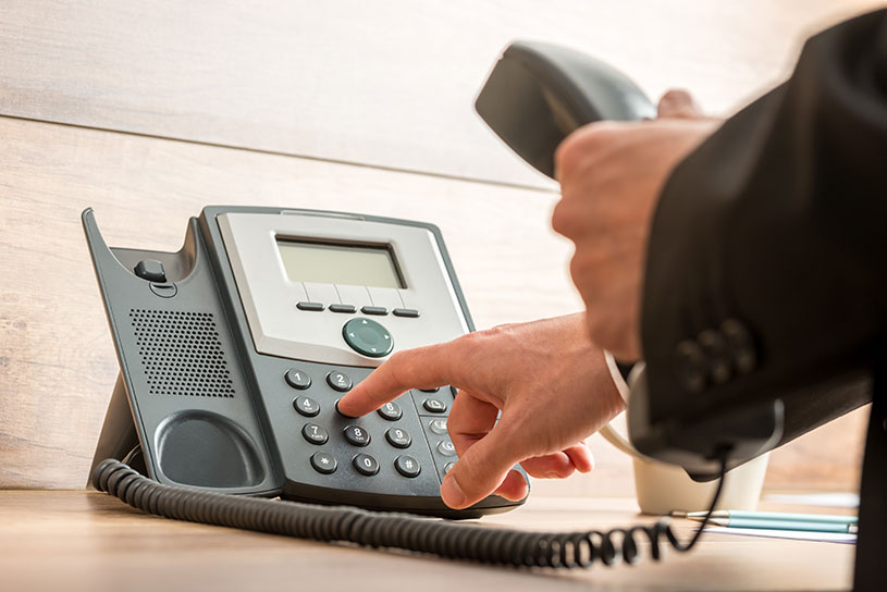 Business man in suit dials a number on a landline phone