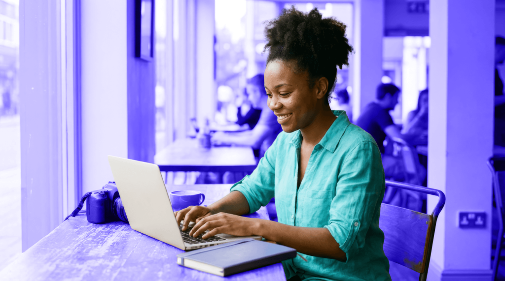 A smiling freelancer works on her laptop in a cafe