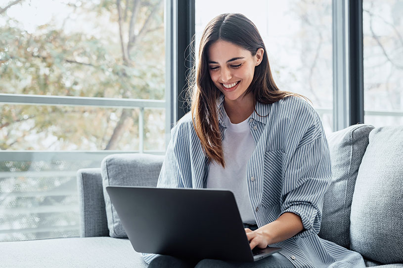 A young woman sitting on a sofa and working on a laptop