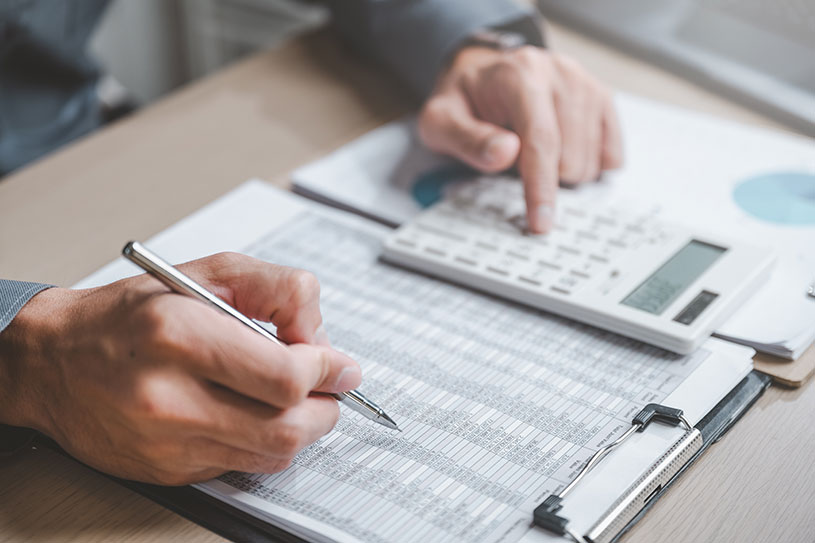 A small business owners works out their payroll using a calculator