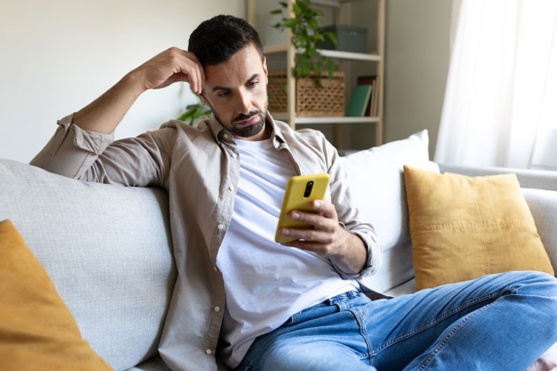 A small business owner worriedly looks at his phone
