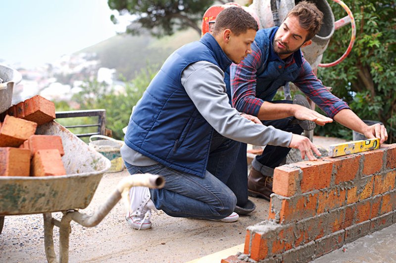 Builder with employee working on a garden wall