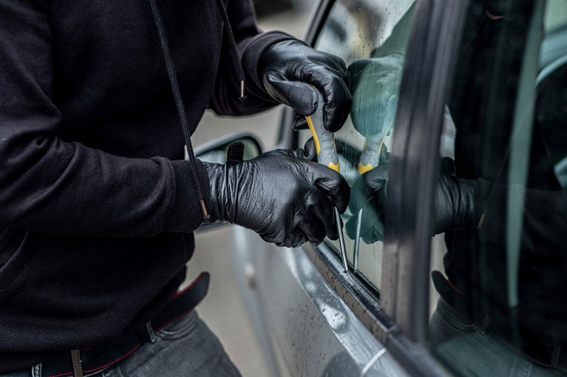 Gloved hands breaking into a vehicle
