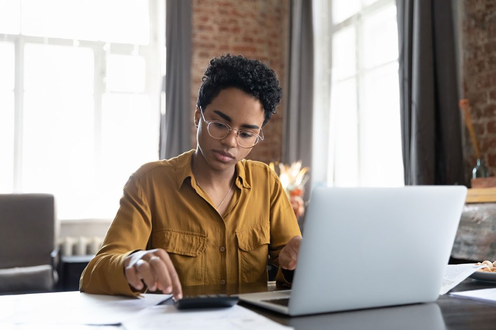 Woman using a calculator and laptop to work out ROI