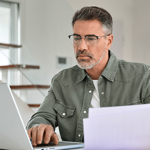 Man in a green shirt working on a laptop