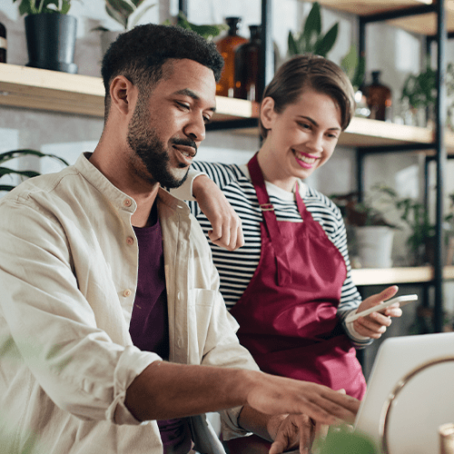 Two people in a plant shop looking at a laptop
