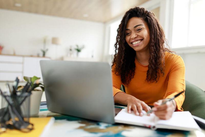 A female business owner works happily on her laptop