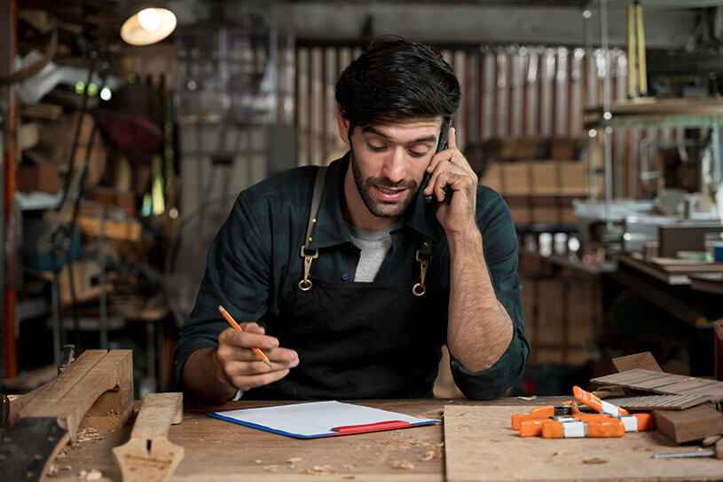 Business owner in workshop on phone to client