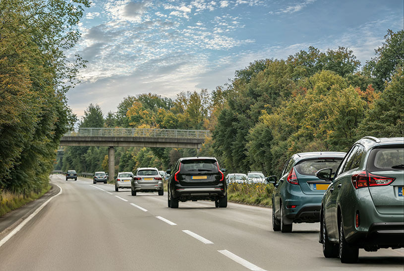 Cars on A road, motorway, Autumn landscape. Autumn trees. Cars driving on a road. Sussex. UK. Britain.