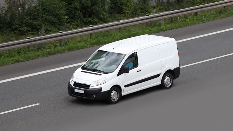 White work van drives along the road
