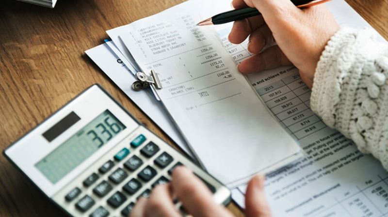 A small business owner works out their expenses for their quarterly reporting using a calculator