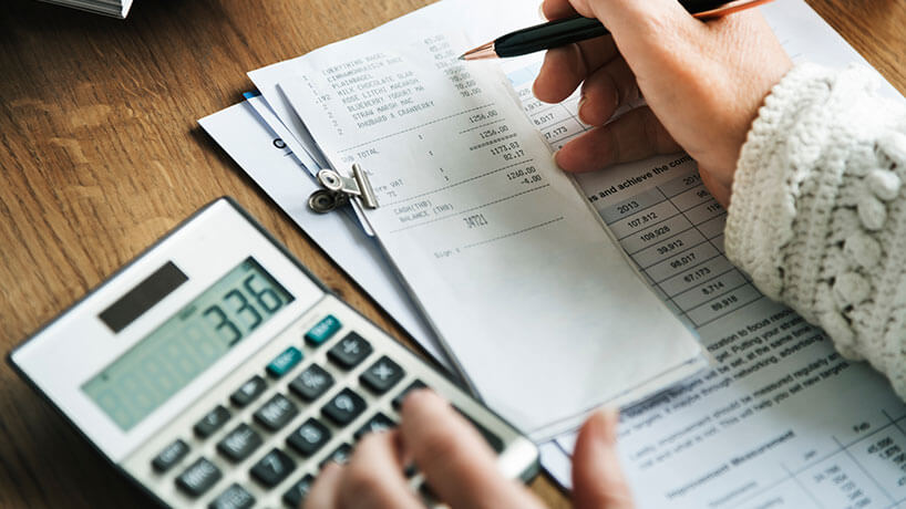 A small business owner works out their expenses for their quarterly reporting using a calculator