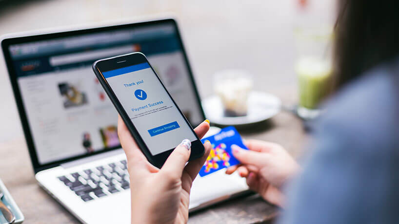 Woman buying a product from an online shop with her phone and a credit card