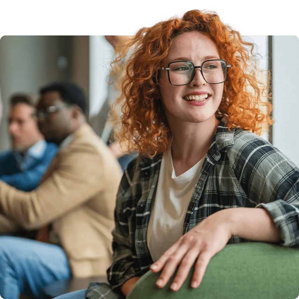 A small business owner looking thoughtfully to the side with a smile in a modern, collaborative office space.